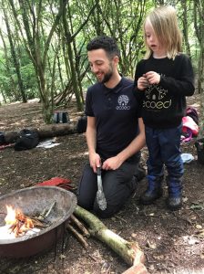 Adult teaches child at Eco Ed Forest School over Manchester half term